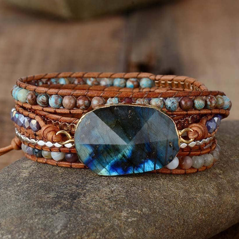 Multistrand beaded bracelet with a large blue stone on a stone surface.
