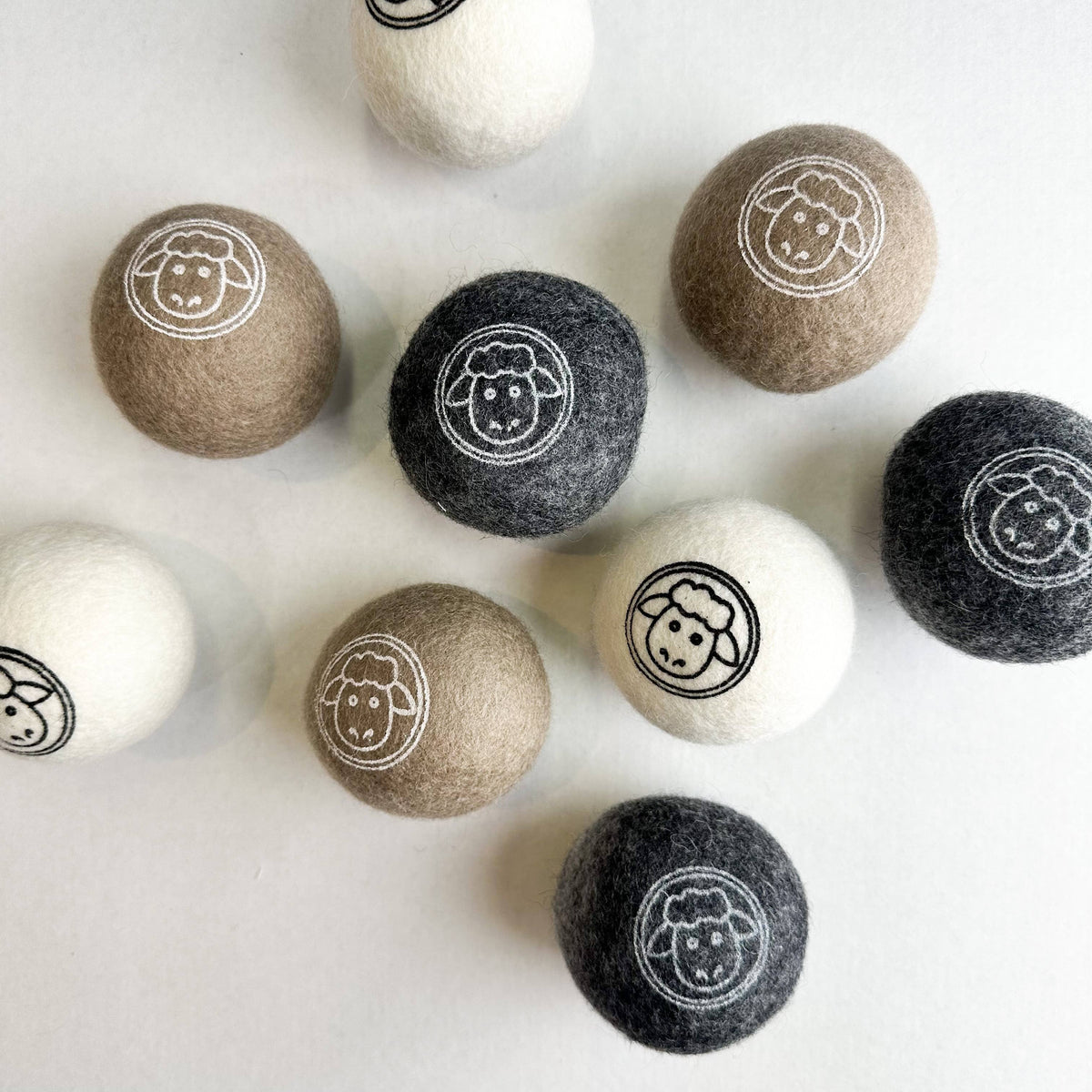 Set of natural wool dryer balls with sheep emblem on a white background