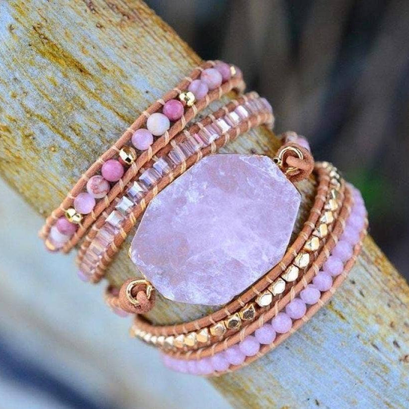 Pink stone bracelet with gold accents on a wooden surface