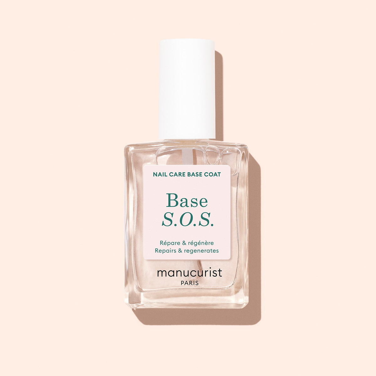 Manucurist S.O.S. Base 15 mL bottle on a pale peach background