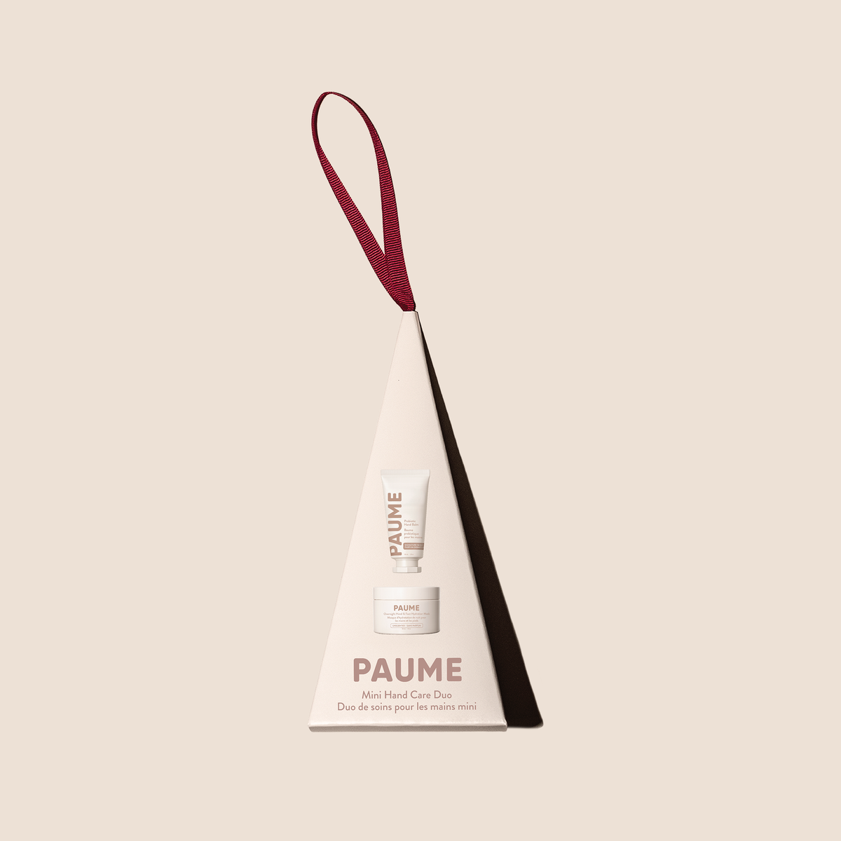 PAUME Mini Hand Care Set in a white cone-shaped gift box with a burgundy hanging loop, shown on a solid beige background.