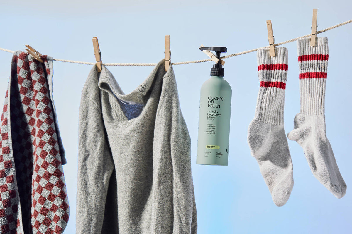 Guests on Earth laundry detergent bottle hanging beside a scarf, knitwear and striped socks.