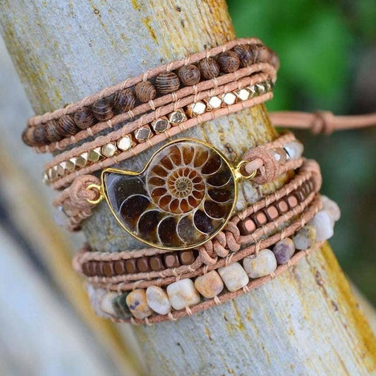 Multistrand bracelet with a fossil pendant on a wooden surface.
