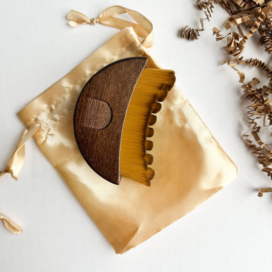 Walnut Lymphatic Brush on a gold satin bag with decorative elements on a light background