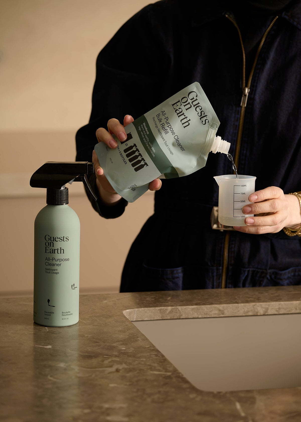 Guests on Earth cleaner spray bottle and refill pouch arranged with greenery and cleaning cloths.