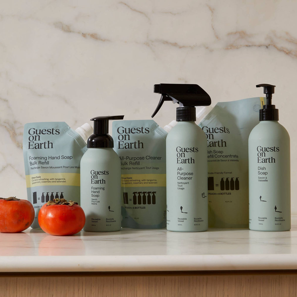 Guests on Earth refill pouches and pump and spray bottles arranged beside citrus fruit.