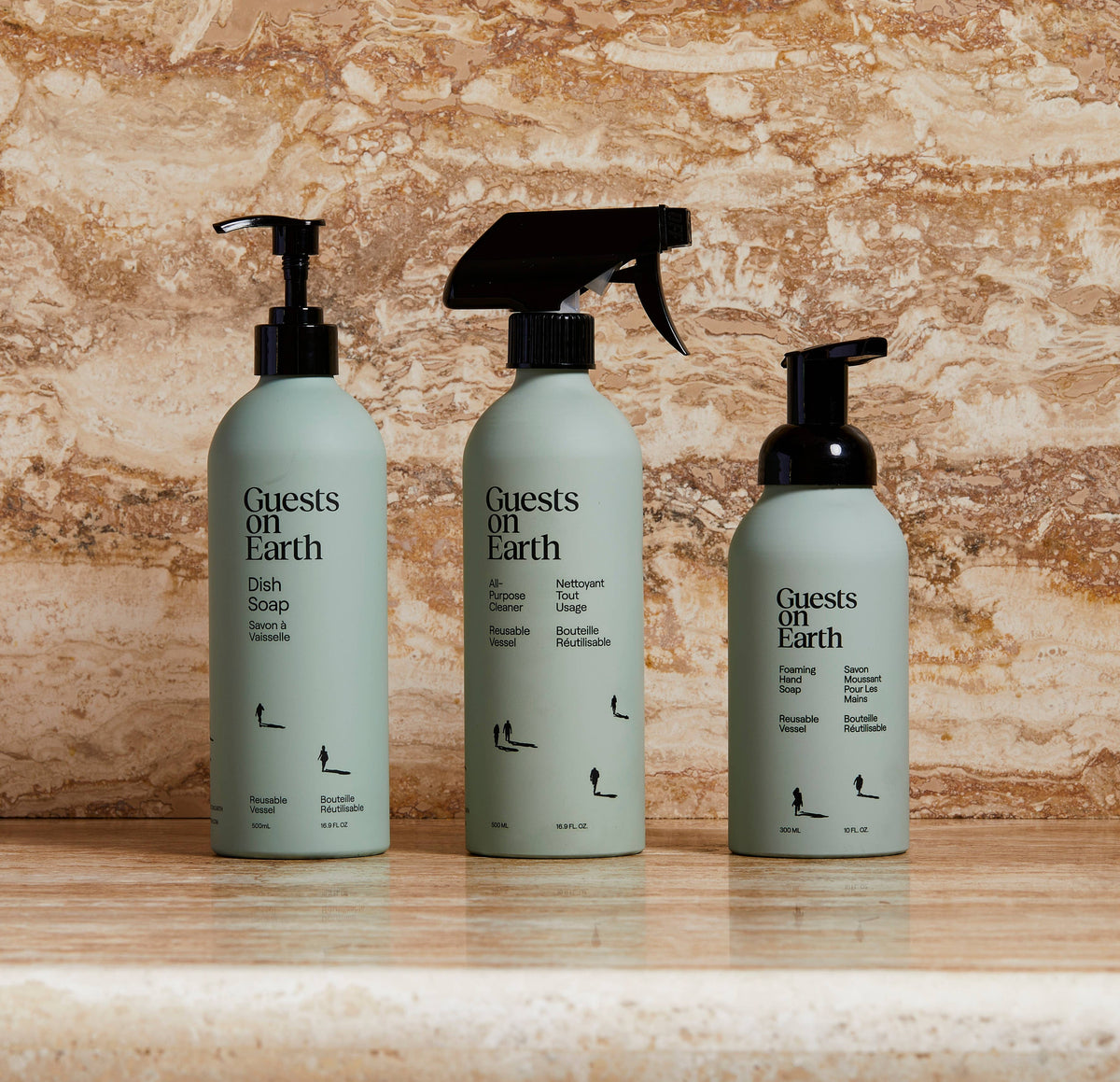 Guests on Earth dish soap, all-purpose cleaner and foaming hand soap bottles on a stone counter.