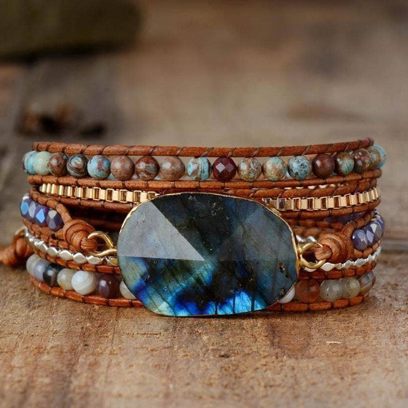 Multistrand bracelet with a large blue stone on a wooden surface.