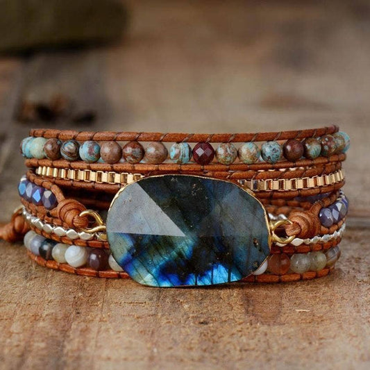 Multistrand bracelet with a large blue stone on a wooden surface.