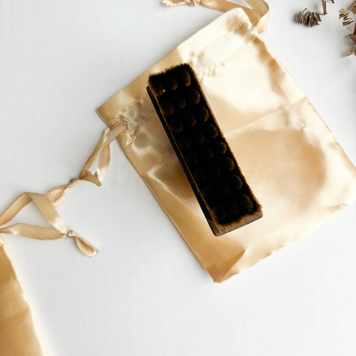 Walnut Lymphatic Brush on a gold satin bag with ribbons on a white background