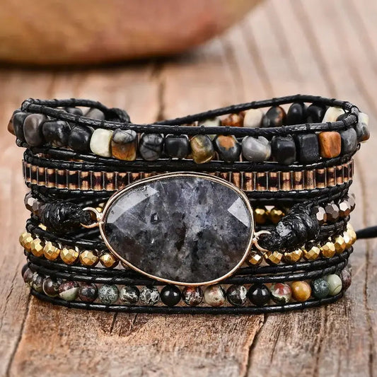 Multistrand beaded bracelet with a central stone on a wooden surface.
