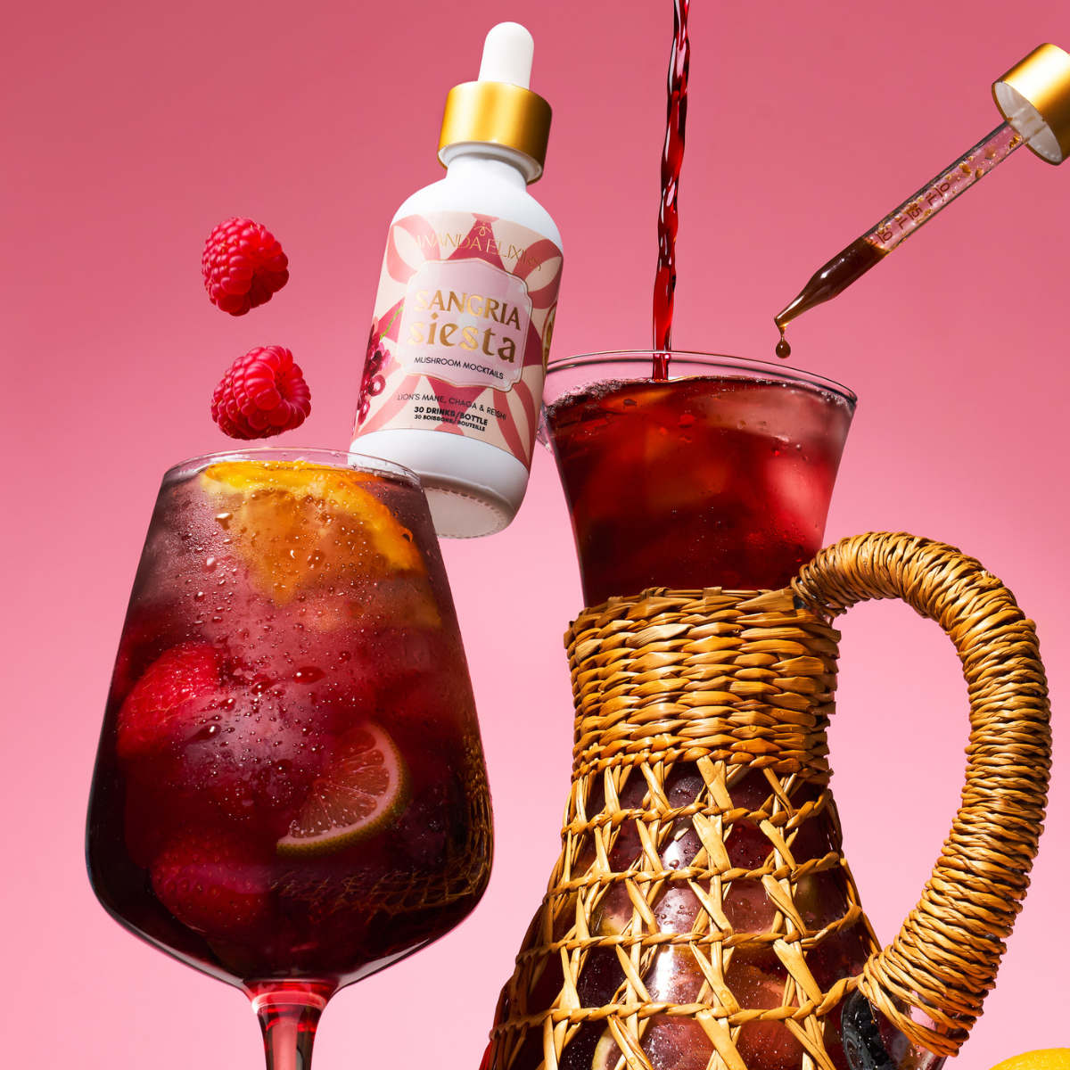 Red drink being poured into a glass with a bottle labeled 'Anará' and raspberries on a pink background.