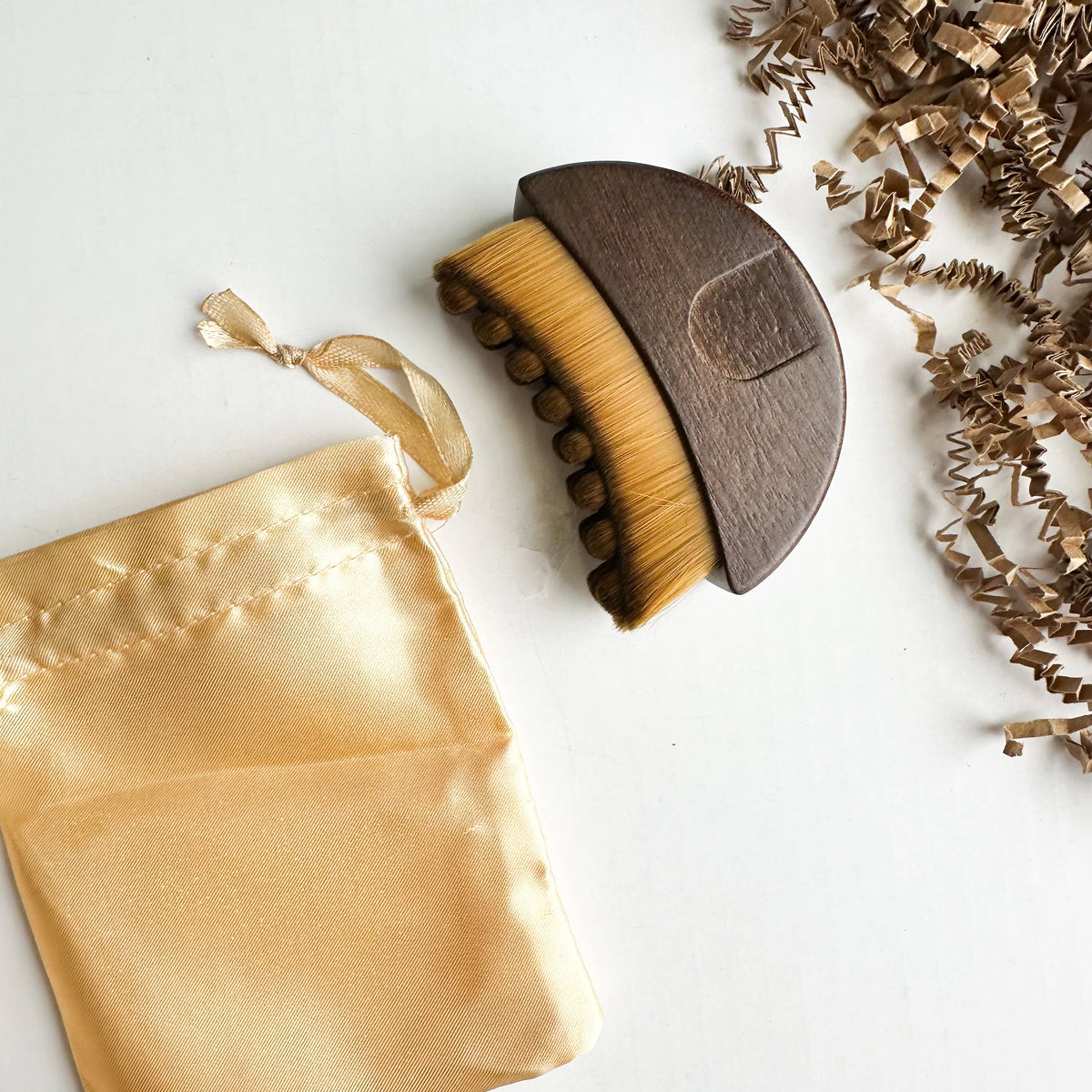 Walnut Lymphatic Brush with a gold satin bag on a white background