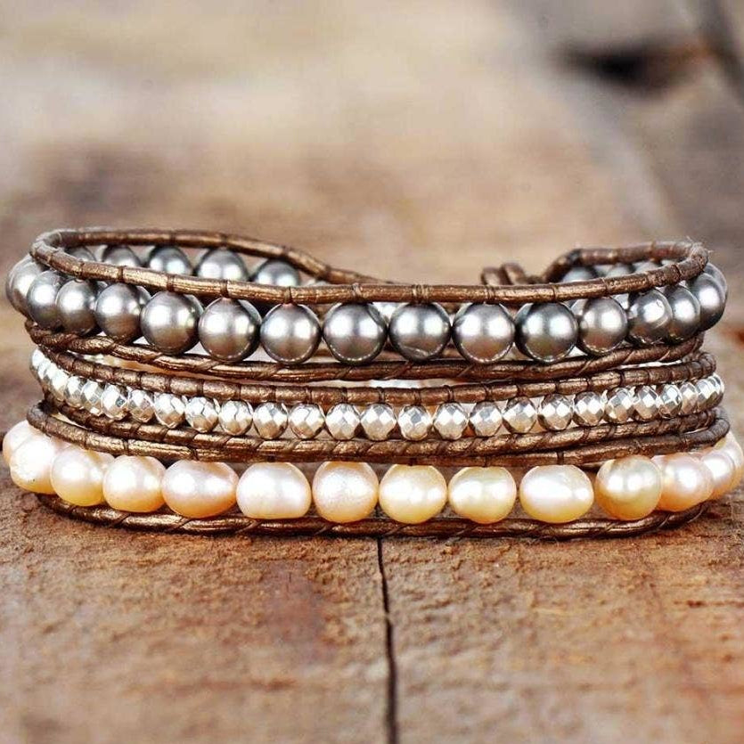 Multi-layered bracelet with pearls and brown leather on a wooden surface