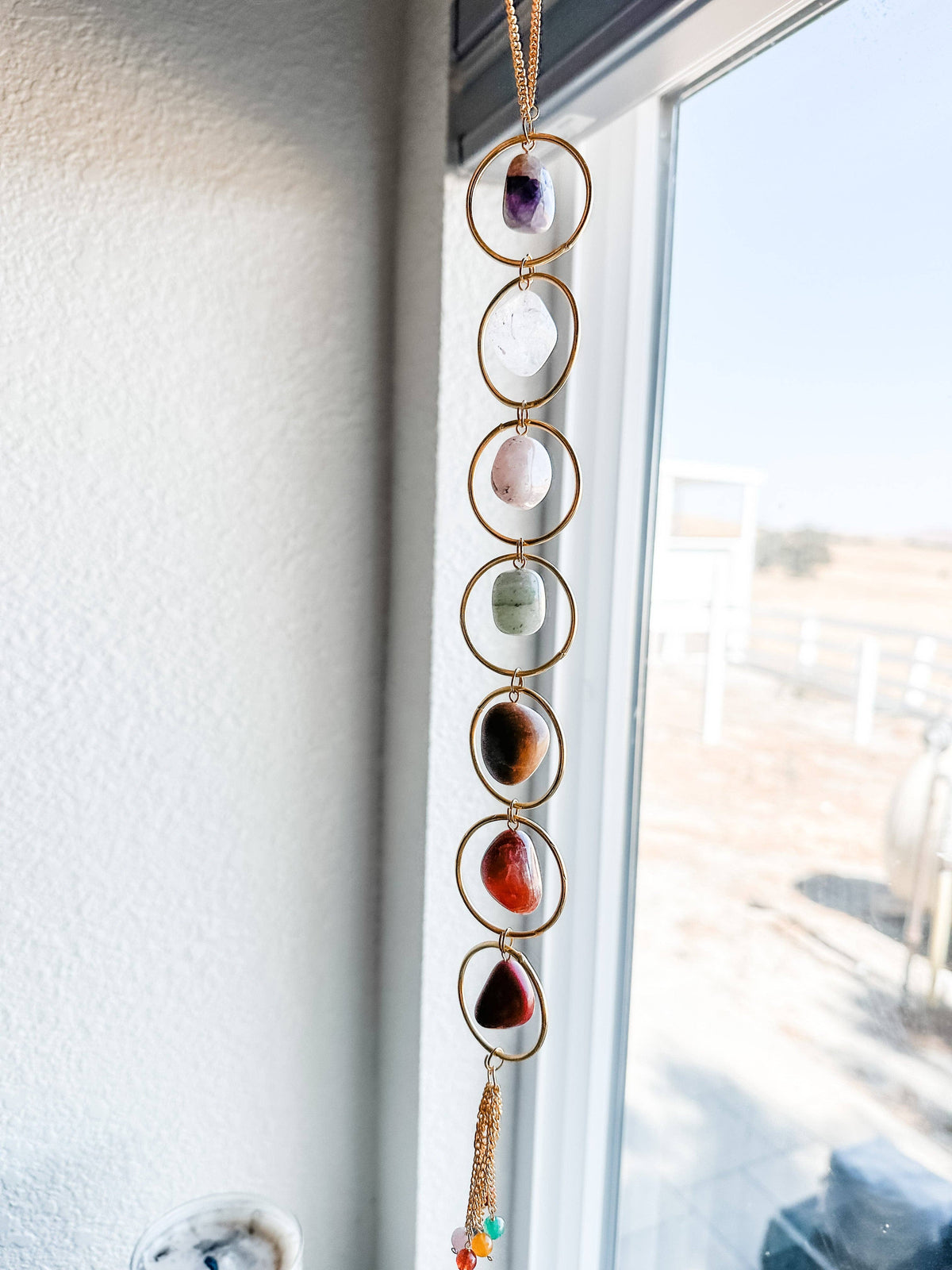 Seven Chakra Crystal Wall Hanging with colorful stones in front of a window