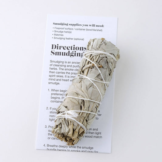 Single small white sage smudge bundle beside its printed smudging directions
