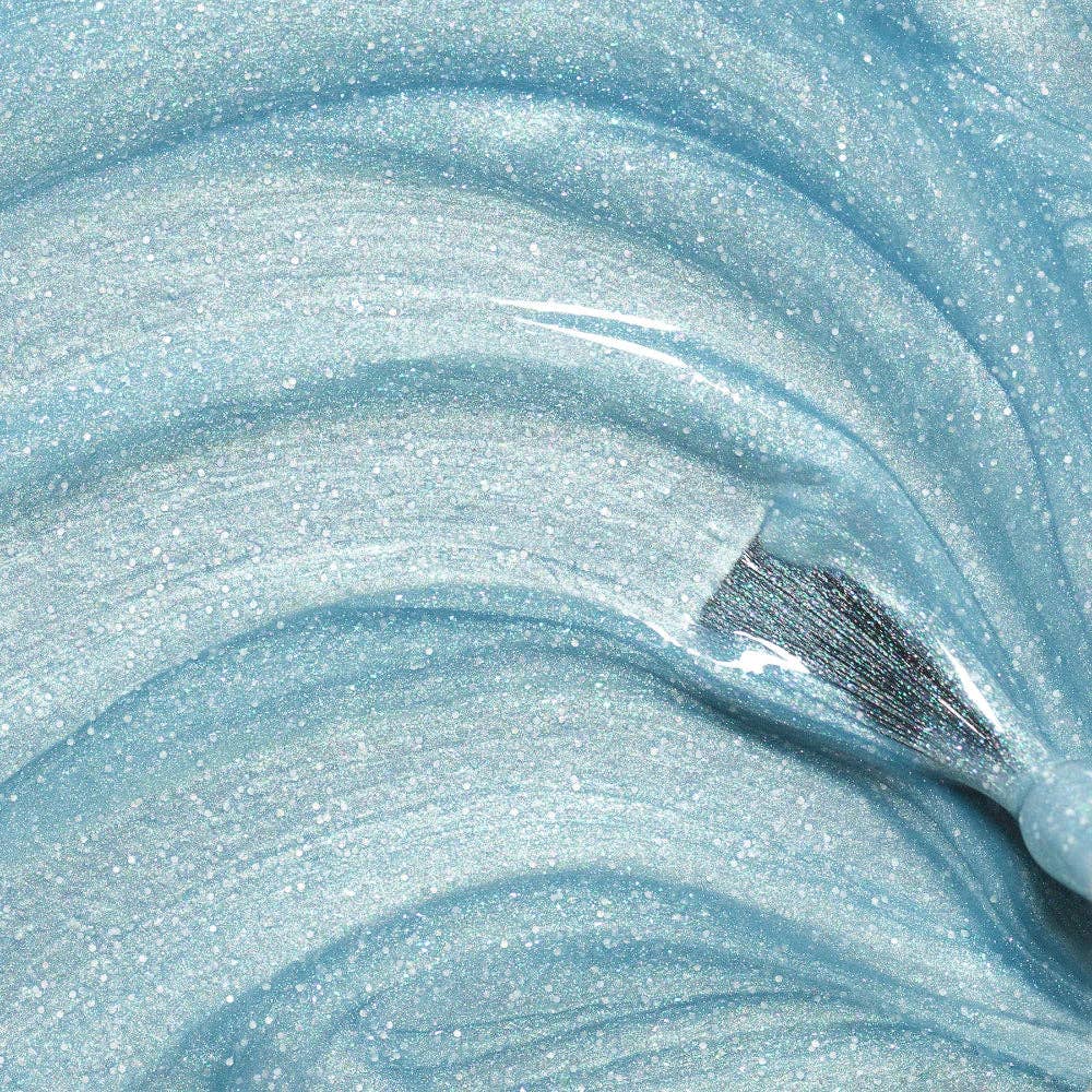 Bonnie blue glitter nail polish with a brush on a blue shimmer background