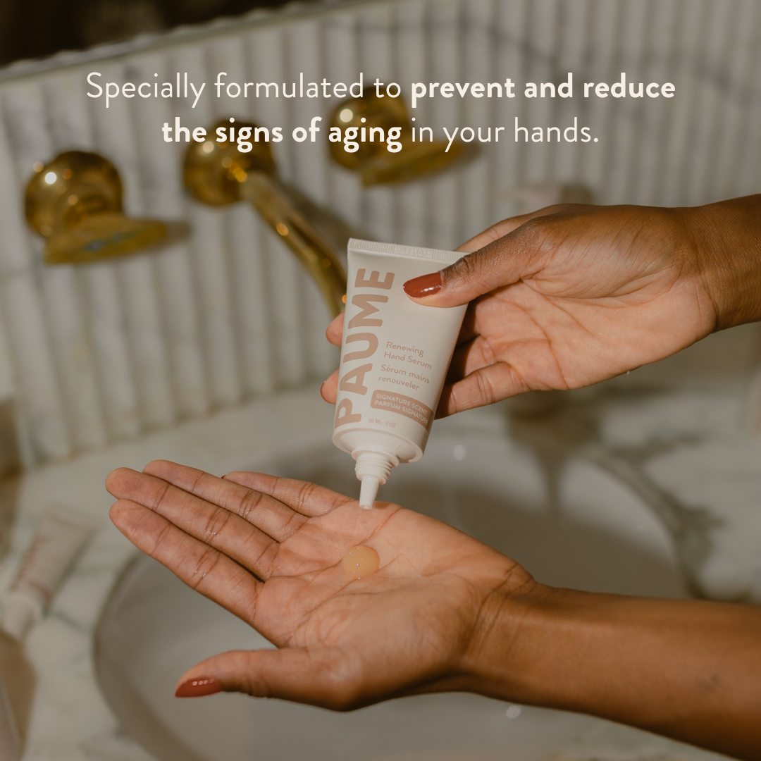 A person squeezes a white tube of PAUME Hand Cream onto their palm in a bathroom setting, with text overlay reading 'Specially formulated to prevent and reduce the signs of aging in your hands.'.