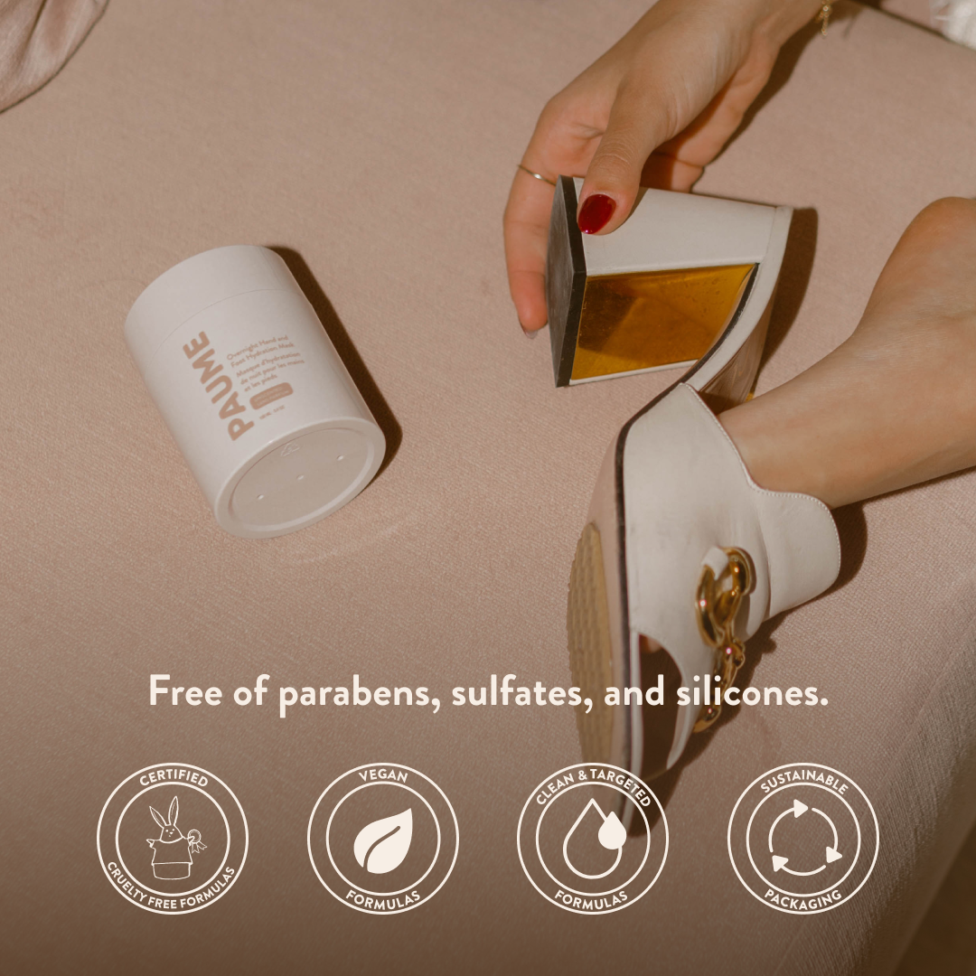Woman applying PAUME Overnight Hand & Foot Hydration Mask to her heel with a jar labeled 'PAUME' on a beige background, featuring sustainability icons.