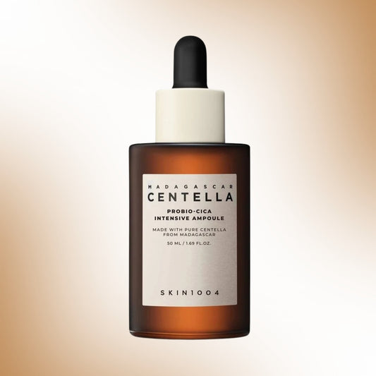 A 50ml amber glass dropper bottle of SKIN1004 Madagascar Centella Probio-Cica Intensive Ampoule, featuring a white label and a black dropper cap, set against a soft beige gradient background.