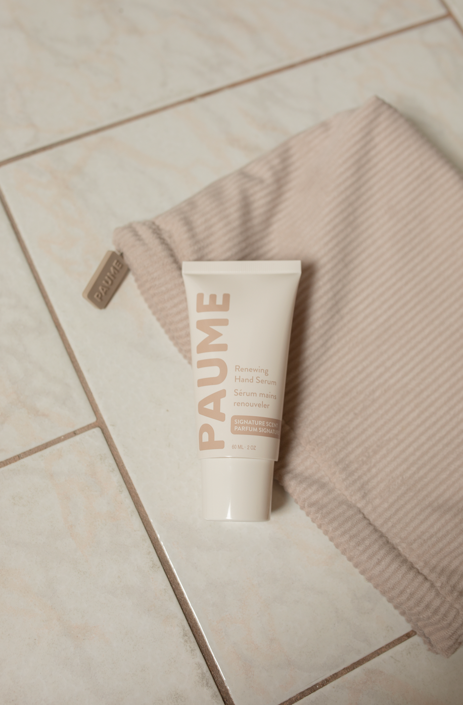 Tube of PAUME serum on a towel on a tiled floor