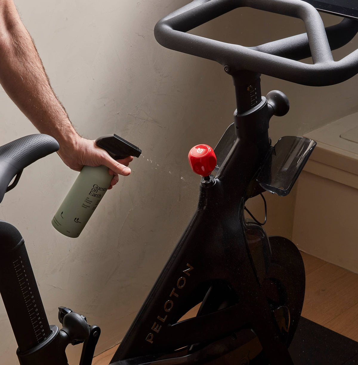 Person using Guests on Earth cleaning spray on an exercise bike.