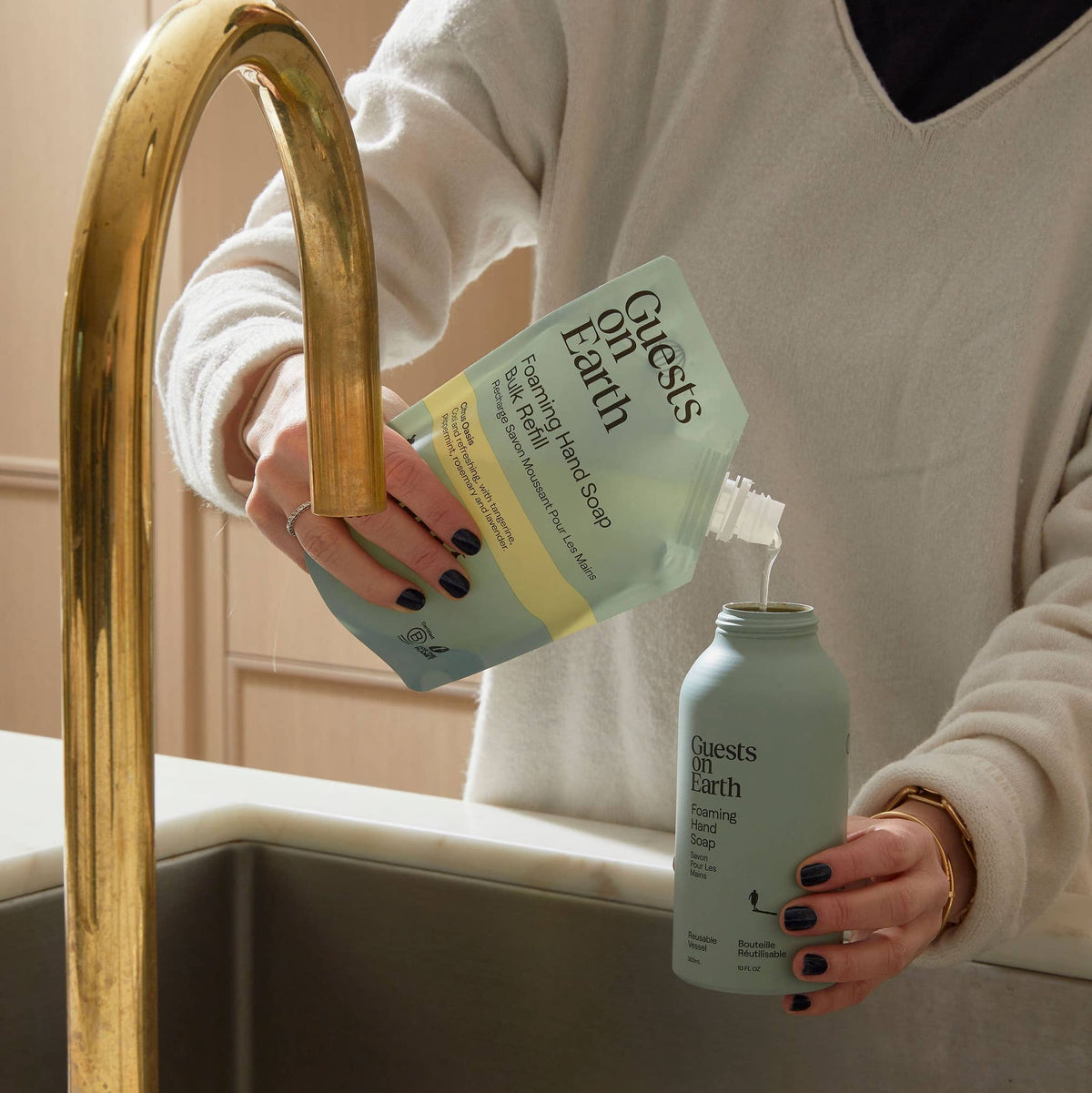 Person pouring Guests on Earth dish soap concentrate from a refill pouch into a reusable bottle.