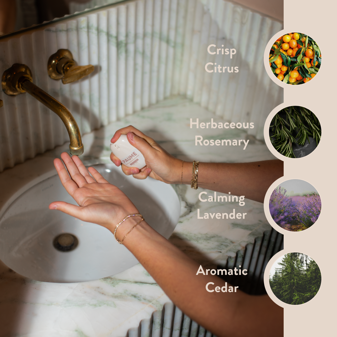 Person holding a bottle of PAUME sanitizer with scents listed on a bathroom background