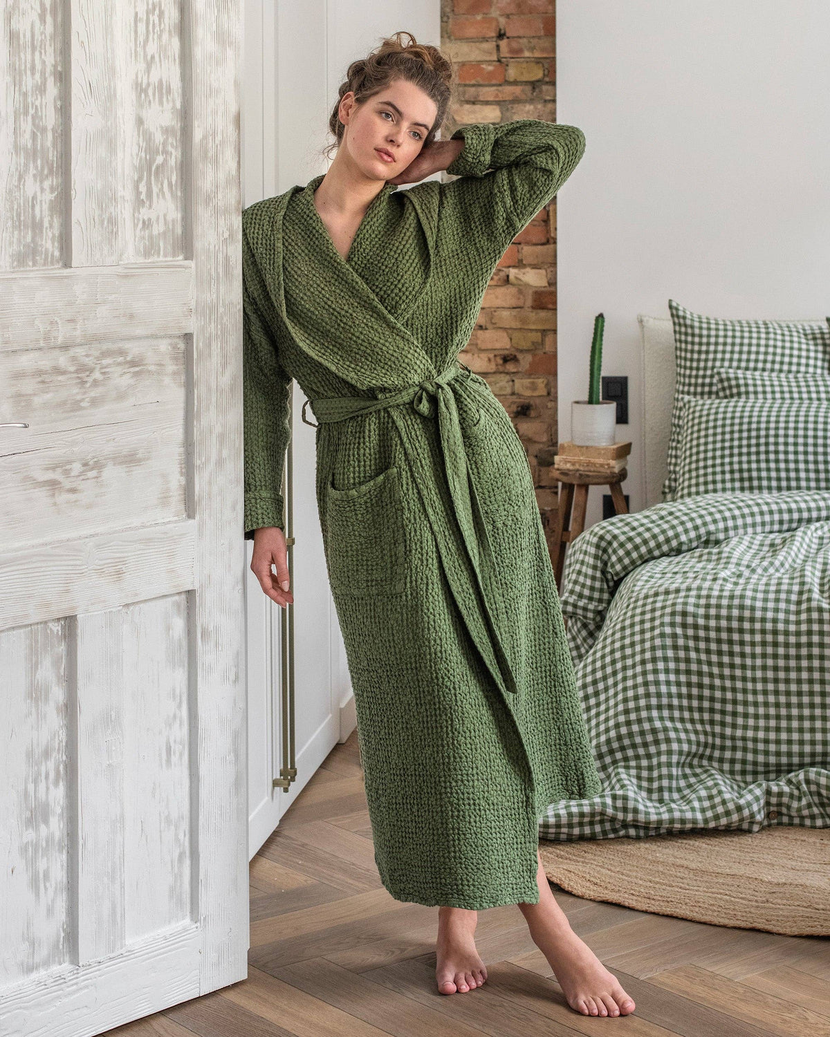Woman wearing a green knitted robe in a bedroom setting.