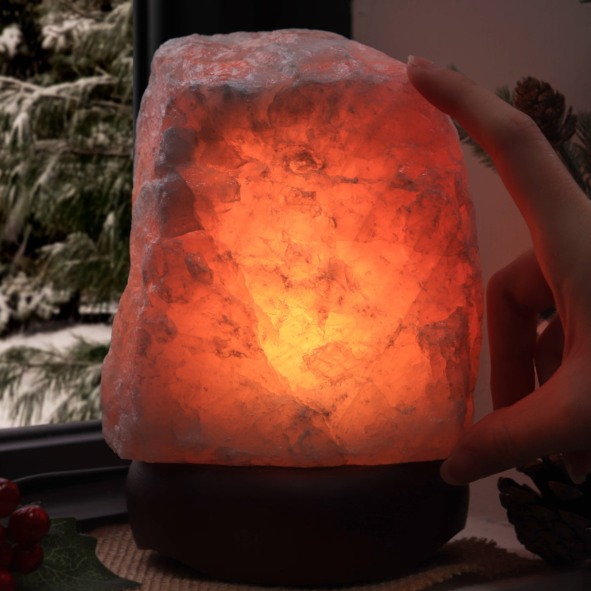 Hand holding a glowing Rose Quartz lamp with a blurred natural background