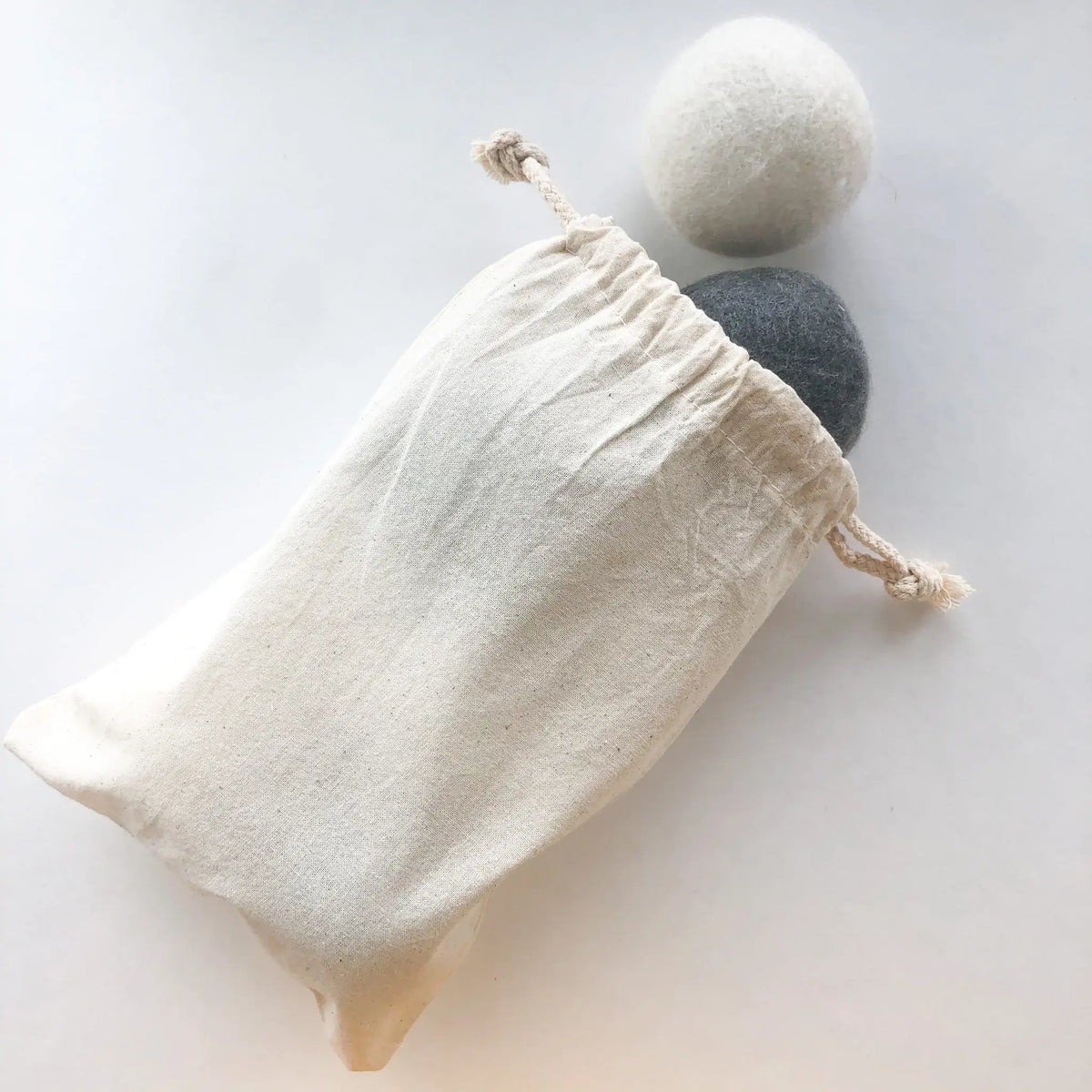 Two all natural dryer balls in a drawstring bag on a light background