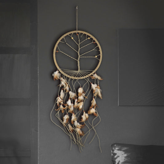 A natural jute dreamcatcher with a tree design hanging on a dark gray wall, featuring brown and white feathers.