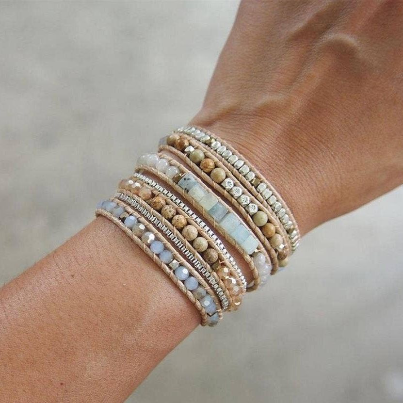 Close-up of a wrist wearing multiple beaded bracelets with a blurred background.