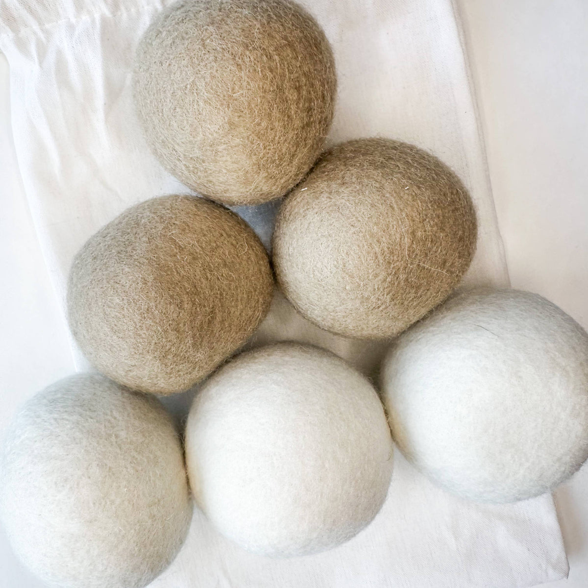 Set of six beige and white wool dryer balls on a white background