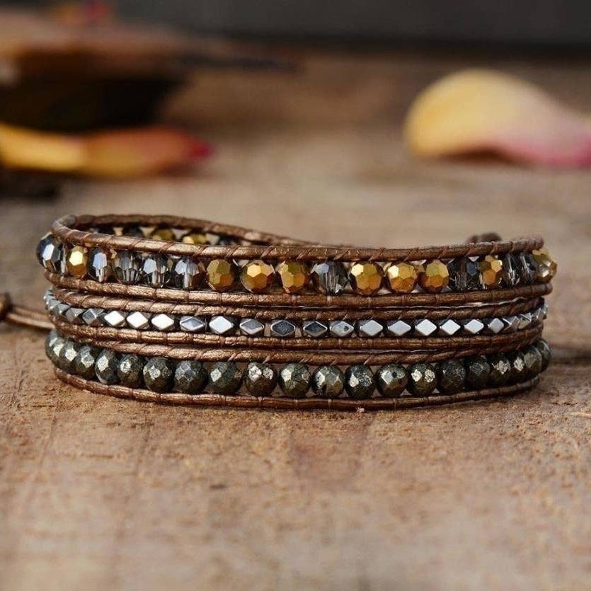 Multi-layered leather bracelet with beads on a wooden surface.