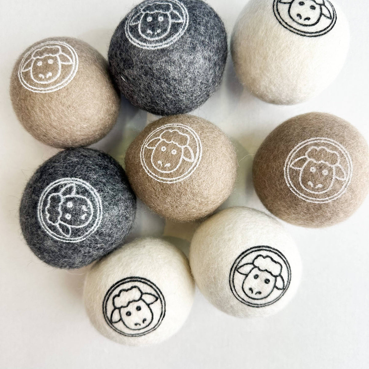 Set of nine all natural wool dryer balls with sheep designs on a white background