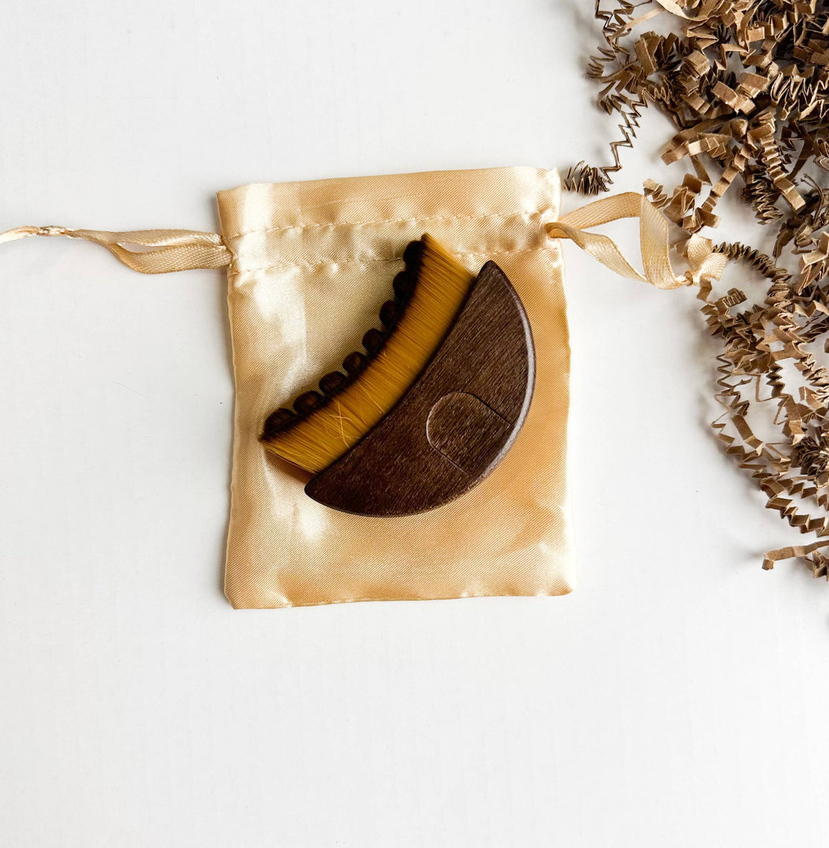 Walnut Lymphatic Brush in a gold drawstring bag on a white background
